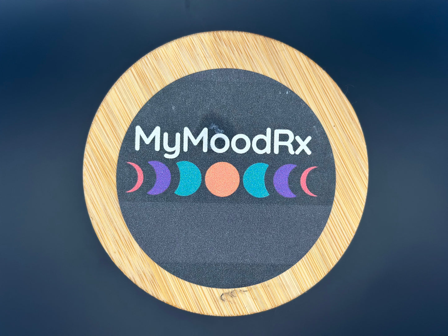 MyMoodRx logo on a circular wooden coaster with a dark background